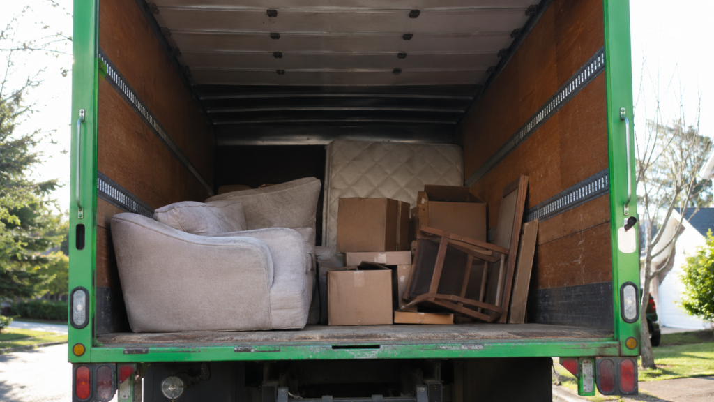 junk removal truck bed partially filled with furniture and boxes showing volume-based pricing